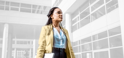 woman with laptop walking through an office building